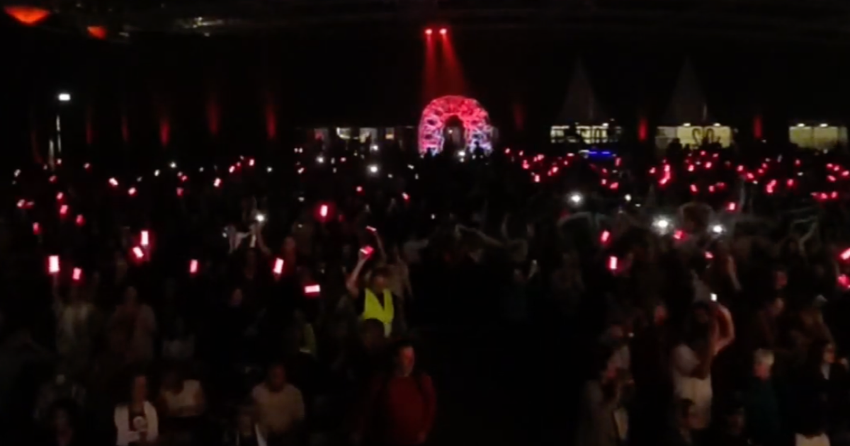Audience at a live event holding up phones with synchronized lights